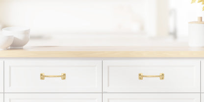 Chanson Hardware larger 4 inch center to center solid brass drawer pull shown on drawer front with unlacquered brass finish
