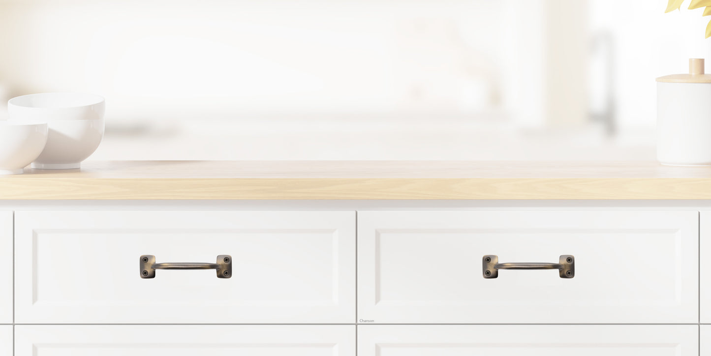 Chanson Hardware larger 4 inch center to center solid brass drawer pull shown on drawer front with antique brass finish
