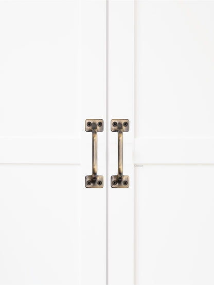 Chanson Hardware solid brass door pull shown on cabinet door in antique brass finish