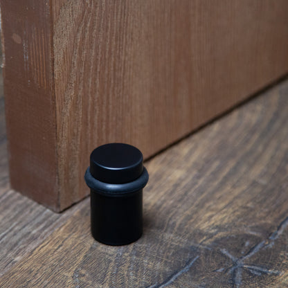 Lifestyle image for chanson hardware 2 inch solid brass cylindrical floor doorstop in flat or matte black finish US19