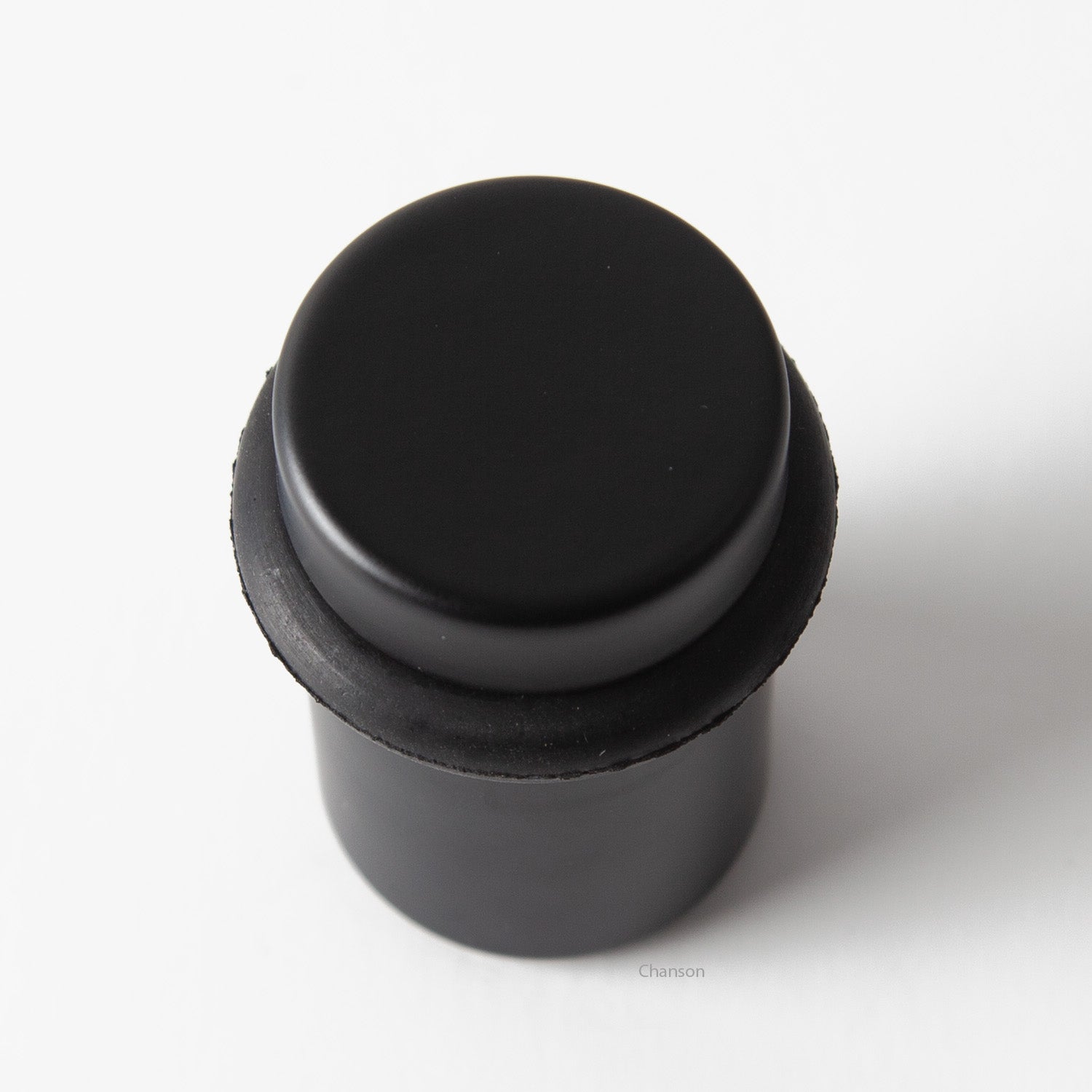 Top view of flat top solid brass cylindrical round floor doorstop in flat or matte black finish US19