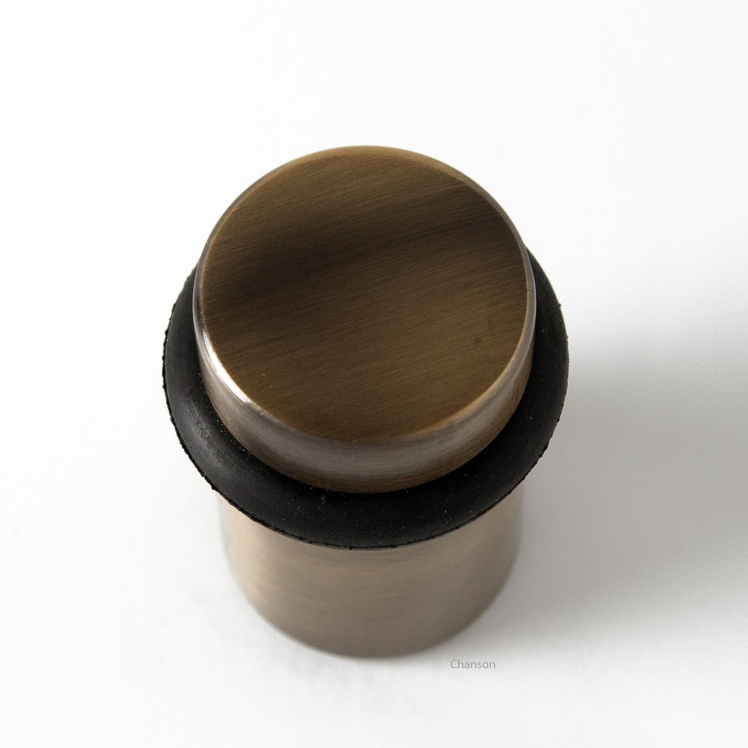Top view of flat top solid brass cylindrical round floor doorstop in antique brass finish US5