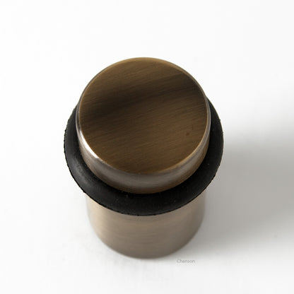 Top view of flat top solid brass cylindrical round floor doorstop in antique brass finish US5