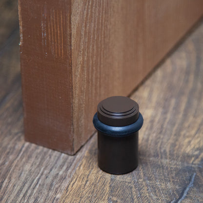 Lifestyle photo for chanson hardware solid brass tiered top floor doorstop, which shows stepped or art deco inspired design and oil rubbed bronze US10B finish.