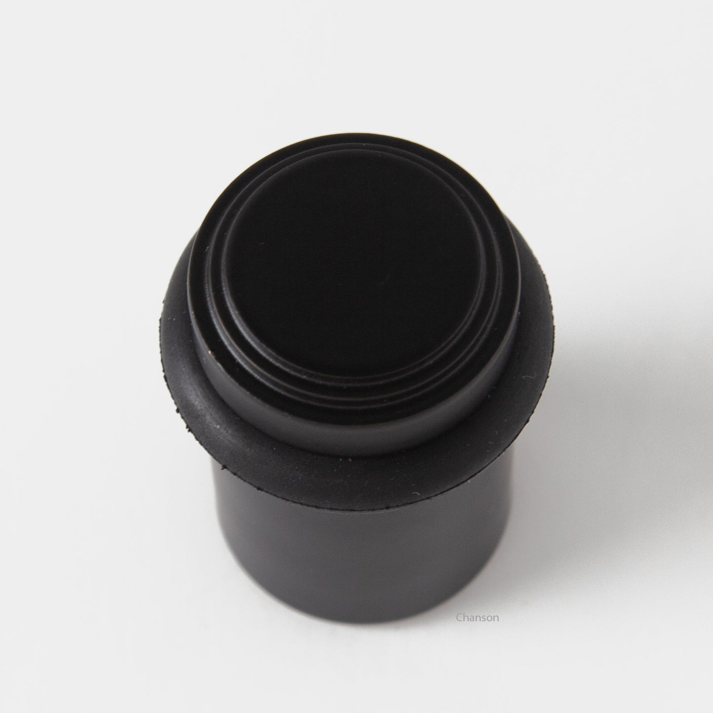 top view of chanson hardware tiered top solid brass doorstop that shows stepped design and cylindrical shape. Finish is flat or matte black US19.  Inspired by Art Deco