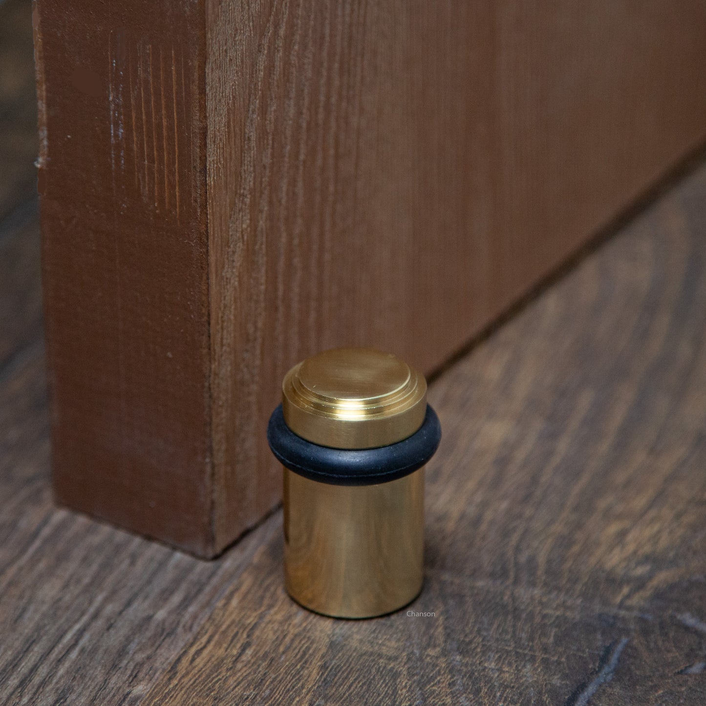 Lifestyle photo for chanson hardware solid brass tiered top floor doorstop, which shows stepped or art deco inspired design and polished brass US3 finish.