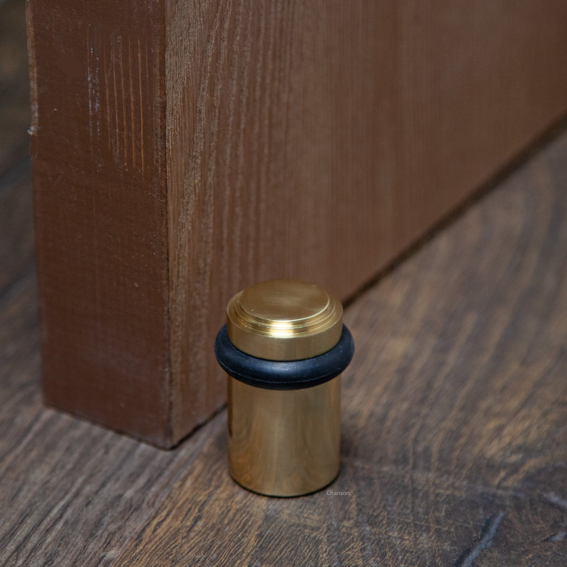 Lifestyle photo for chanson hardware solid brass tiered top floor doorstop, which shows stepped or art deco inspired design and polished brass US3 finish.