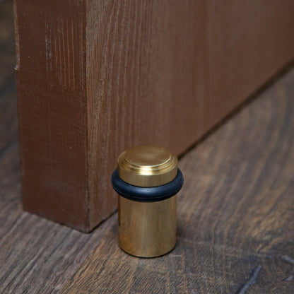 Lifestyle photo for chanson hardware solid brass tiered top floor doorstop, which shows stepped or art deco inspired design and polished brass US3 finish.