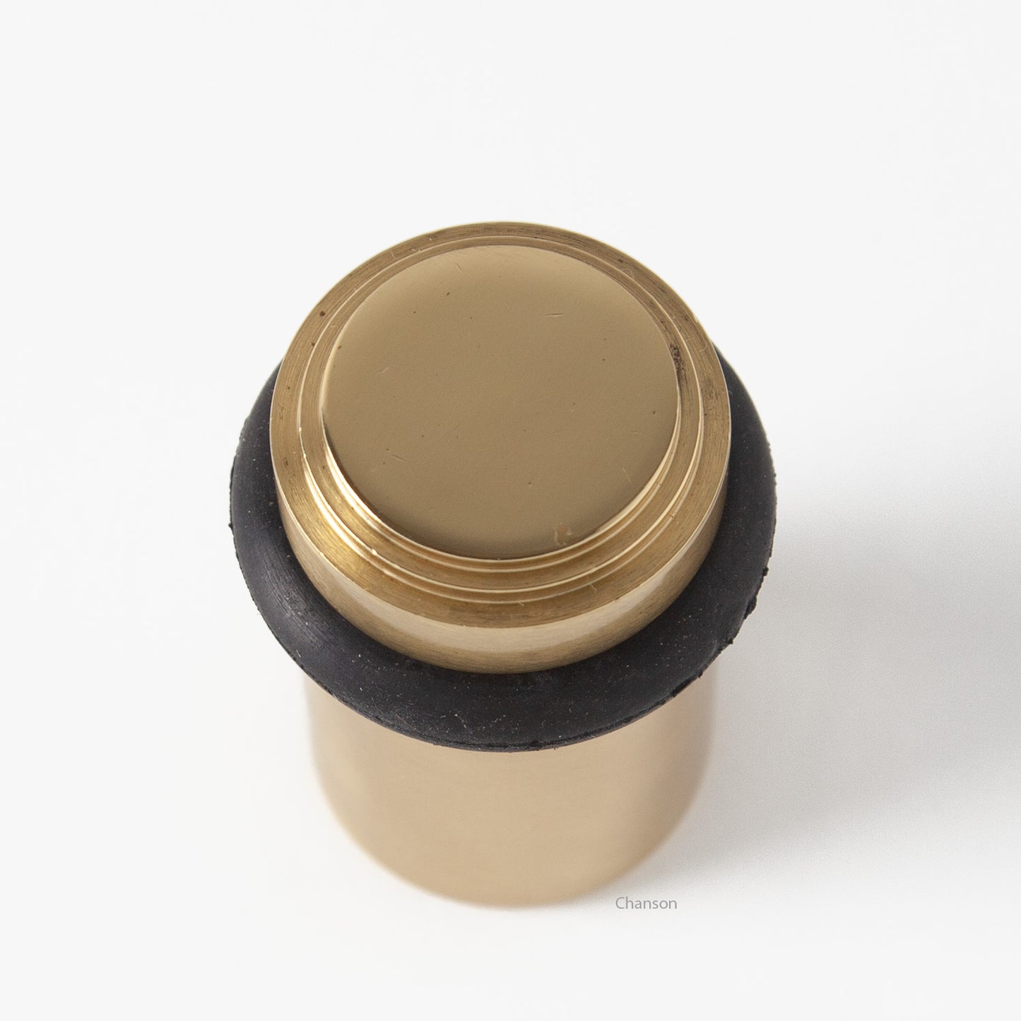 top view of chanson hardware tiered top solid brass doorstop that shows stepped design and cylindrical shape. Finish is polished brass US3.  Inspired by Art Deco