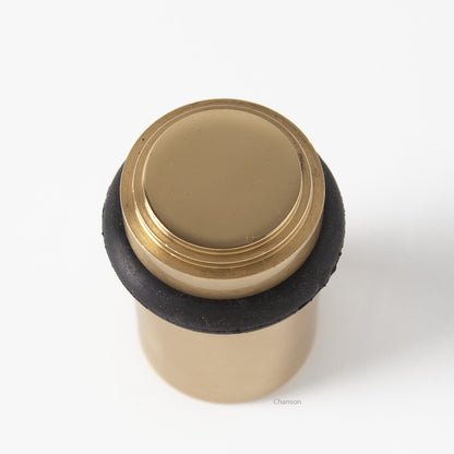 top view of chanson hardware tiered top solid brass doorstop that shows stepped design and cylindrical shape. Finish is polished brass US3.  Inspired by Art Deco