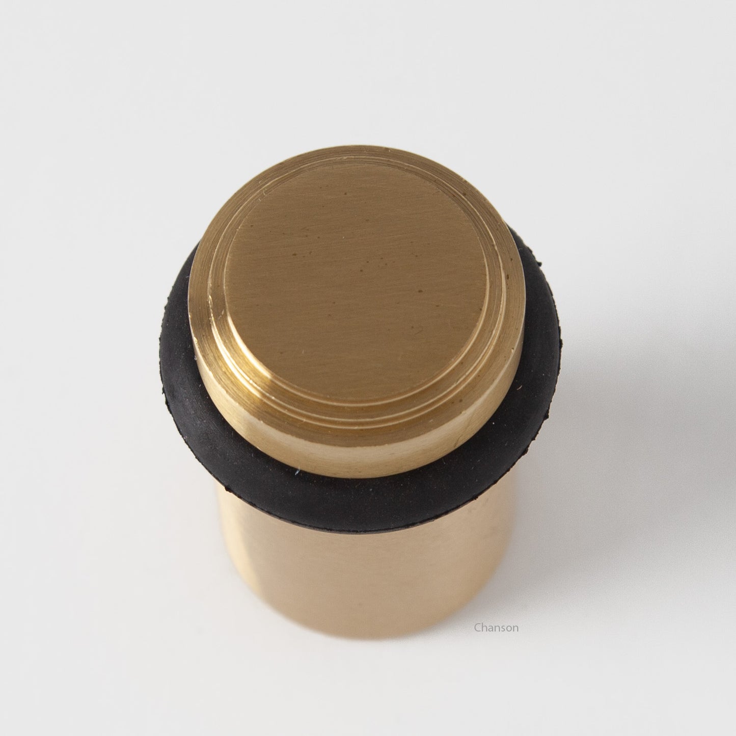 top view of chanson hardware tiered top solid brass doorstop that shows stepped design and cylindrical shape. Finish is satin brass US4.  Inspired by Art Deco