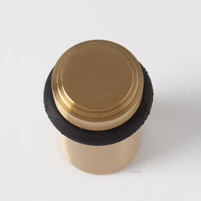 top view of chanson hardware tiered top solid brass doorstop that shows stepped design and cylindrical shape. Finish is satin brass US4.  Inspired by Art Deco