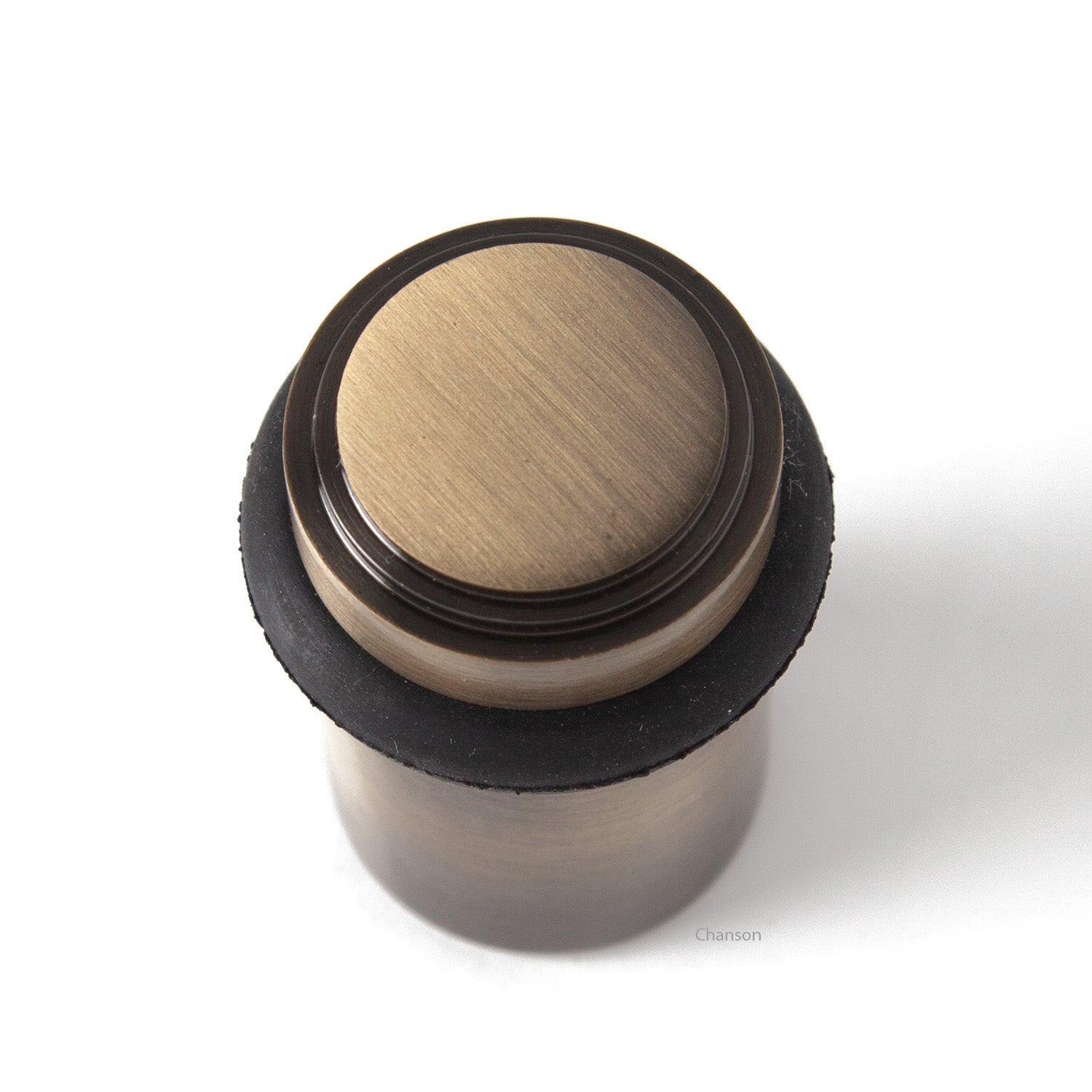 top view of chanson hardware tiered top solid brass doorstop that shows stepped design and cylindrical shape. Finish is antique brass US5.  Inspired by Art Deco