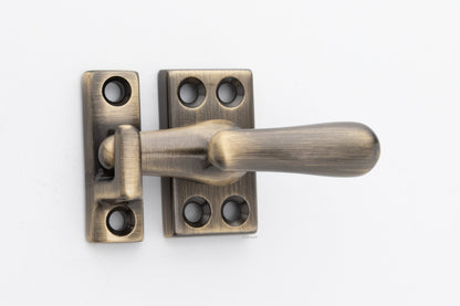 Forged solid brass casement fastener latch unit engaged with surface strike in antique brass US5 finish