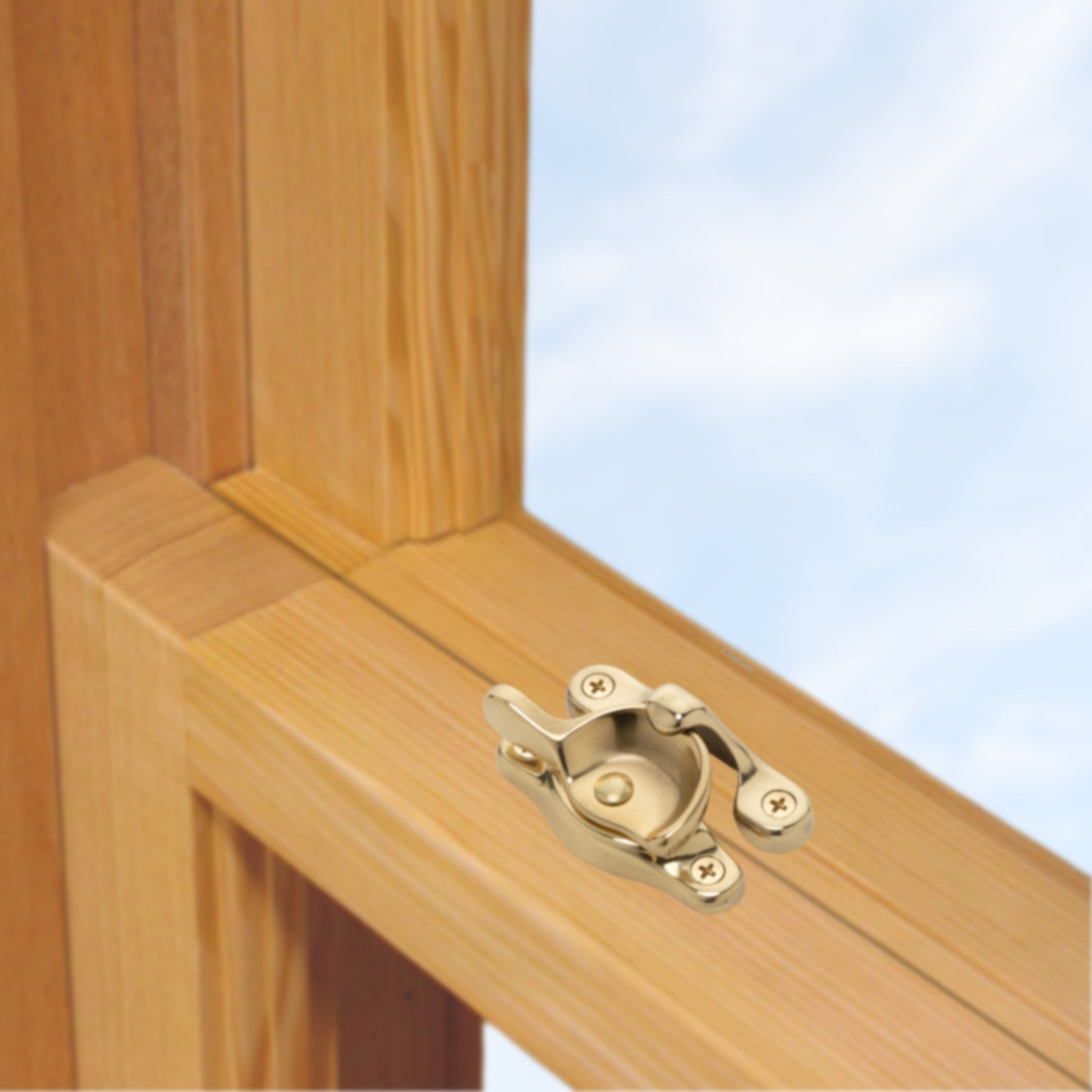 A wooden sash window, single or double hung, with a solid brass sash catch or latch installed on the meeting rail, shown in polished brass finish
