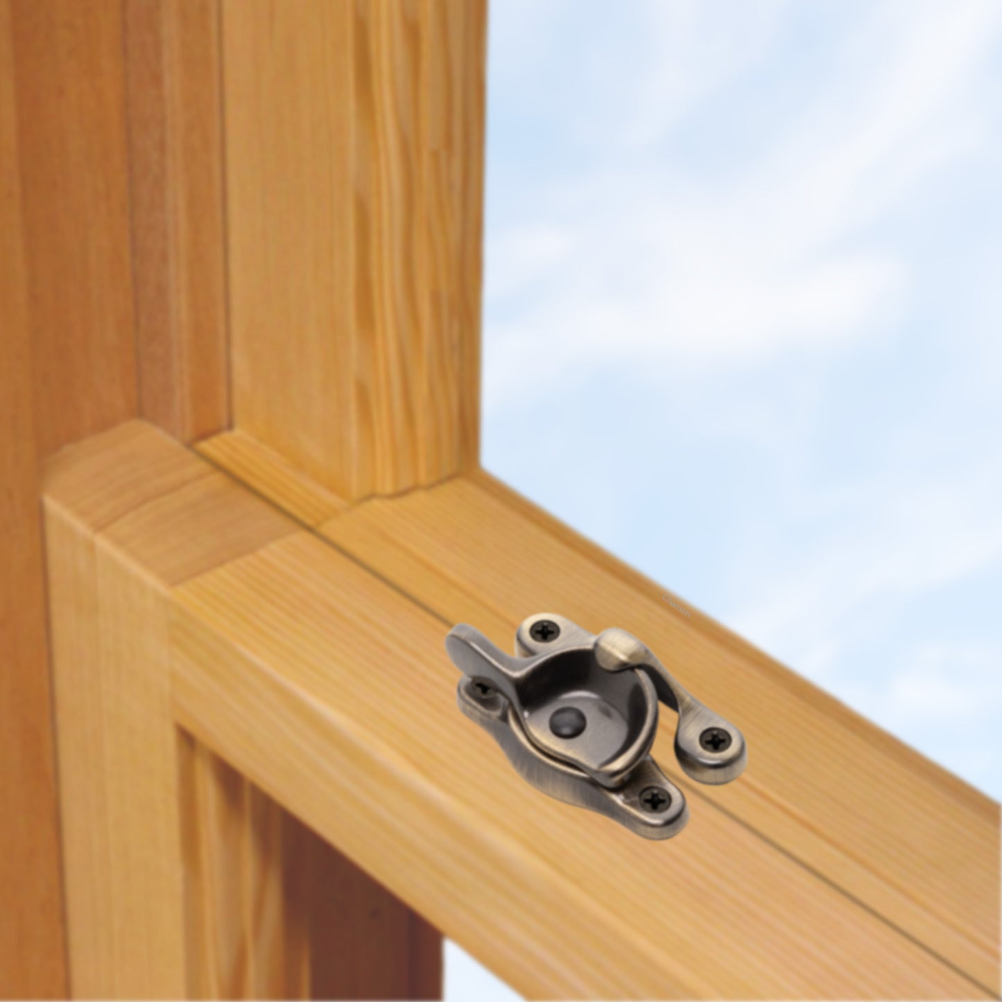A wooden sash window, single or double hung, with a solid brass sash catch or latch installed on the meeting rail, shown in antique brass finish