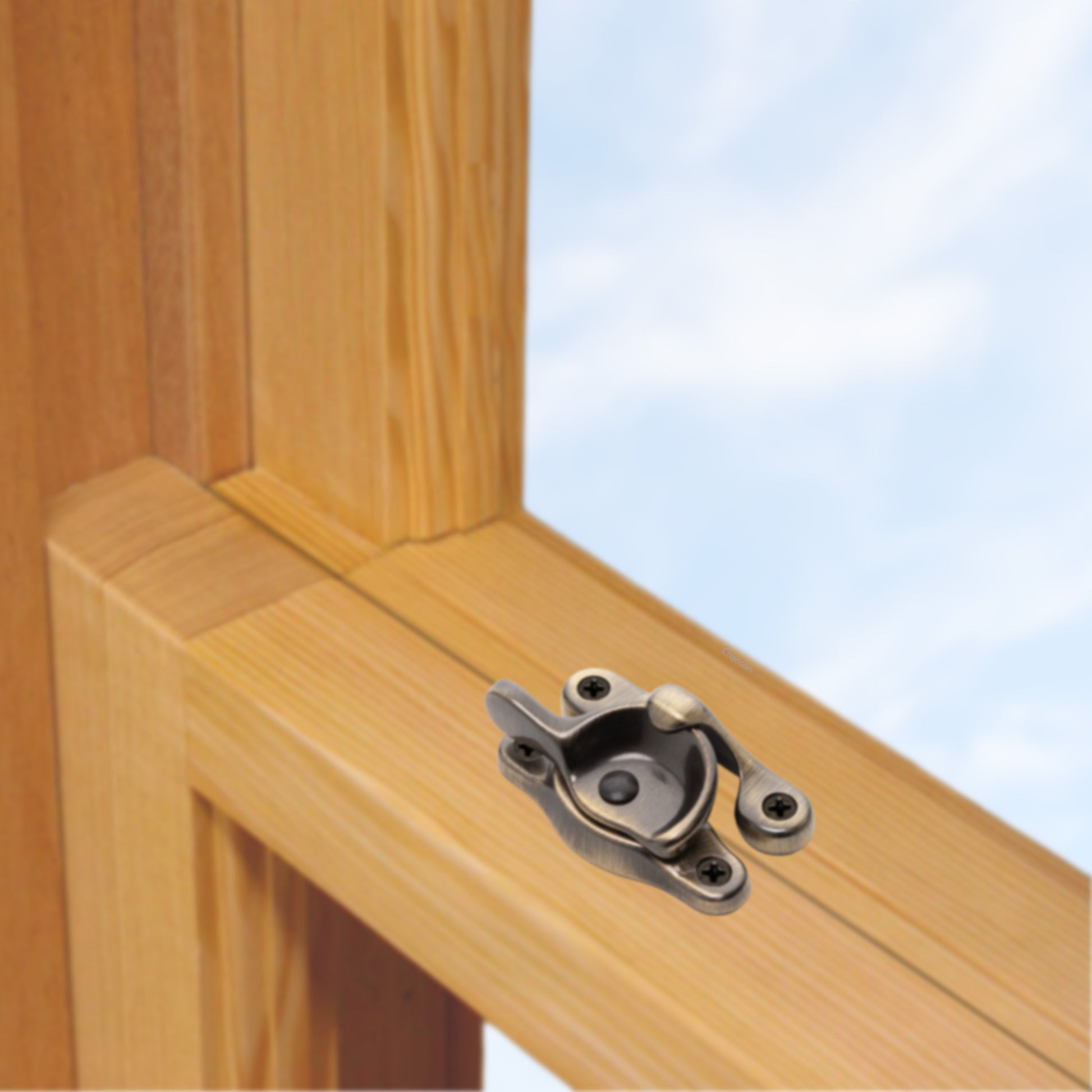 A wooden sash window, single or double hung, with a solid brass sash catch or latch installed on the meeting rail, shown in antique brass finish
