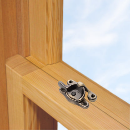 A wooden sash window, single or double hung, with a solid brass sash catch or latch installed on the meeting rail, shown in antique brass finish
