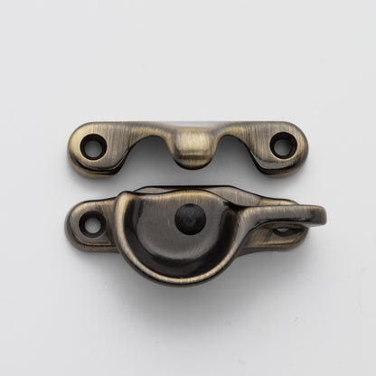 Classic style solid brass sash catch shown with lock turned open. Showcases hook shaped keeper and crescent shaped latch in antique brass US5 finish