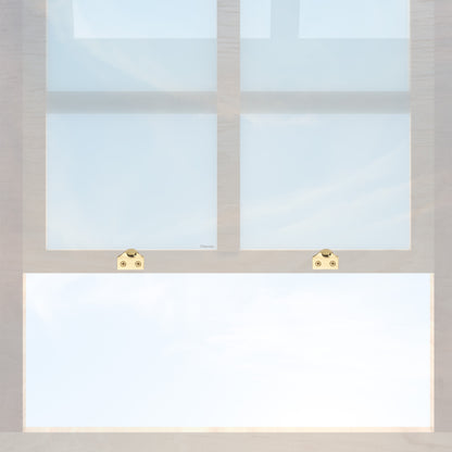 A wooden sash window with a pair of chanson hardware solid brass sash lifts that have a hook type design and an unlacquered brass finish