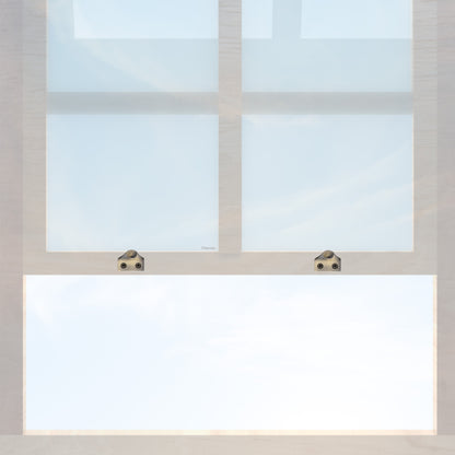 A wooden sash window with a pair of chanson hardware solid brass sash lifts that have a hook type design and an antique brass finish 