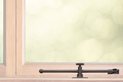 A sliding rod design solid brass casement adjustable stay with knob adjuster that is installed on the bottom sill or ledge of a outward swing window, shown in oil rubbed bronze finish